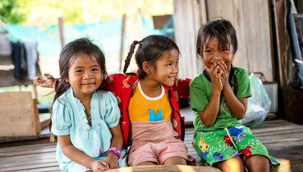Tre søstrer smiler mot kameraet i Kambodsja