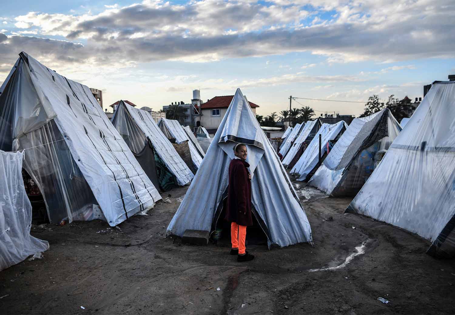 Jente står utenfor teltet sitt i Gaza.