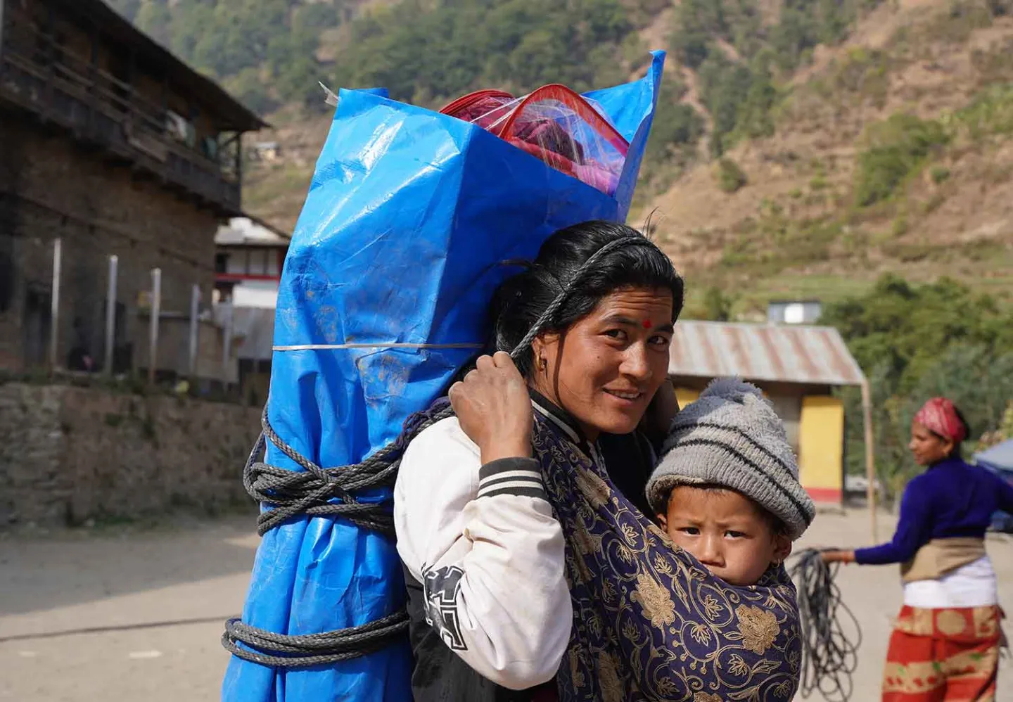 Kvinne i Nepal får nødvendig utstyr fra en midlertidig flytningsleir.