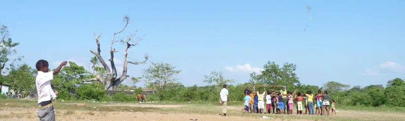 gutt-som-flyr-drage-ved-gruppe-barn-colombia-2000x600