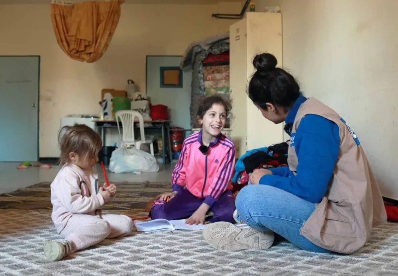 Eleen og Aseel snakker med en Plan-ansatt på internatet der de bor.