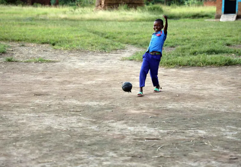 En gutt spiller fotball i Malawi.